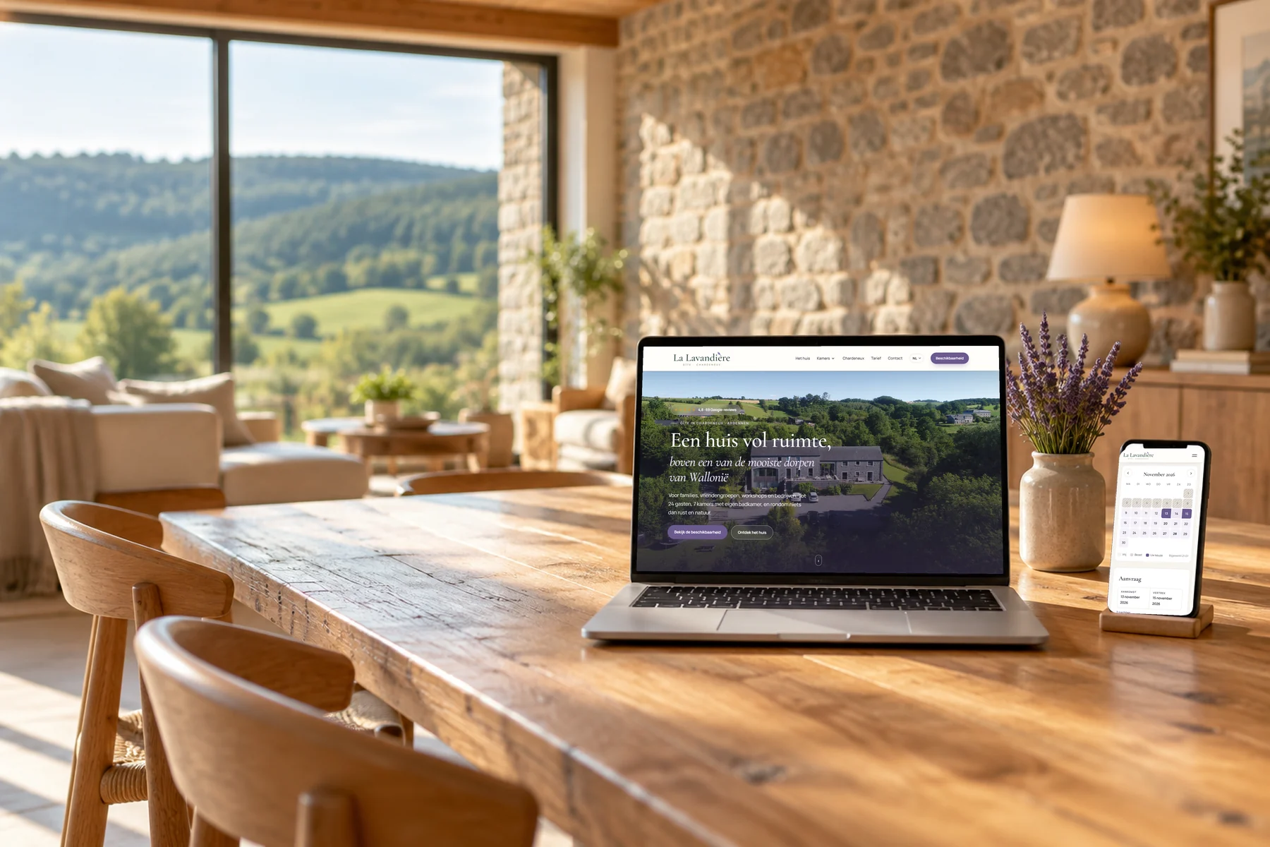 Website van La Lavandière op een laptop en de beschikbaarheidskalender op een smartphone, op een houten tafel in een stenen vakantiehuis met zicht op de heuvels