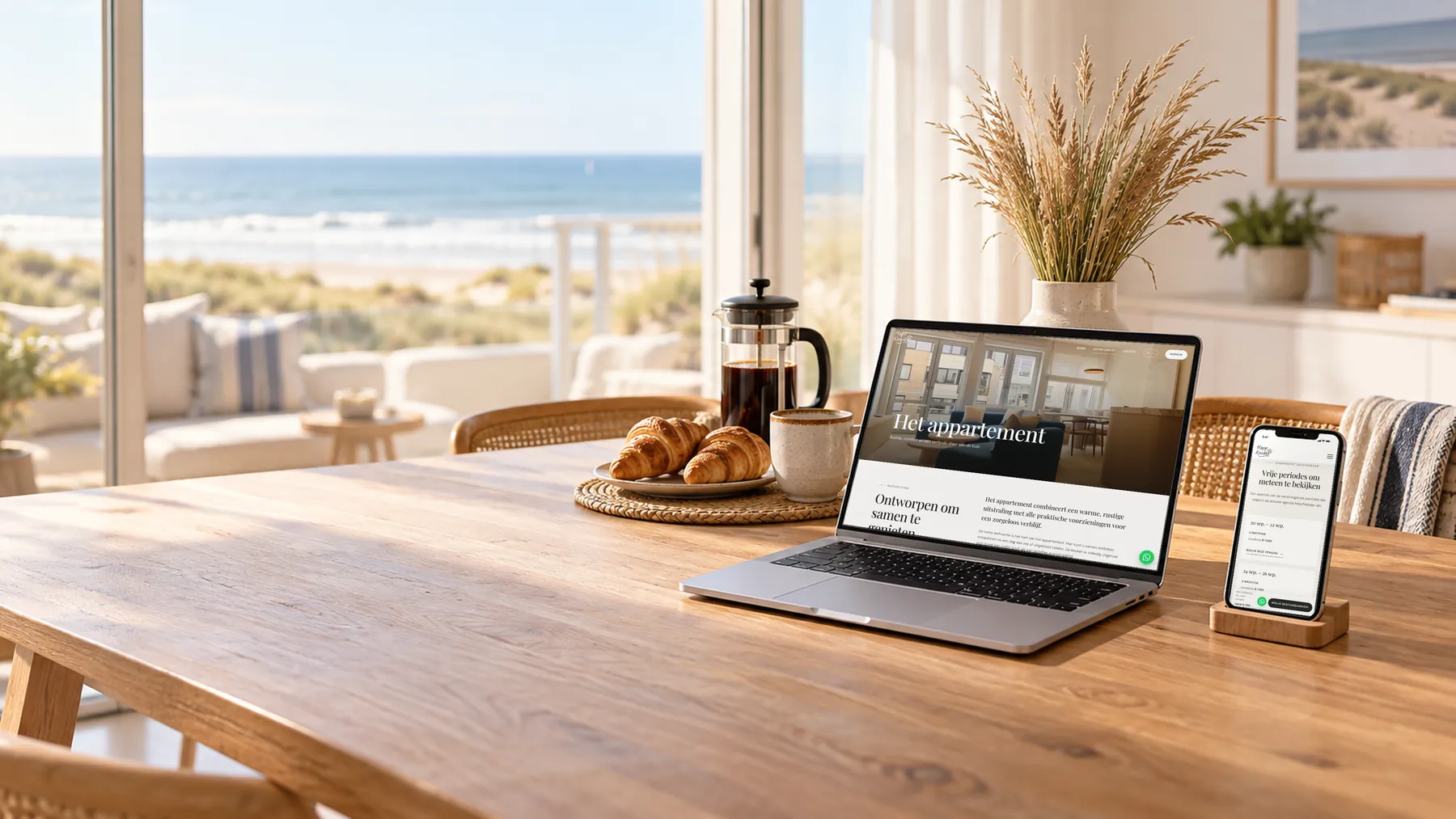 De website van Happ Knokke op een laptop en de vrije periodes op een smartphone, op een ontbijttafel in een appartement met zicht op zee